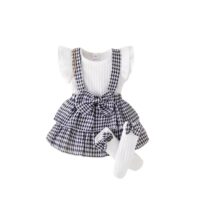 Toddler girl houndstooth suspender skirt set with ribbed white top, ruffled sleeves, pleated front, and black & white houndstooth skirt with waist bow, displayed for catalog