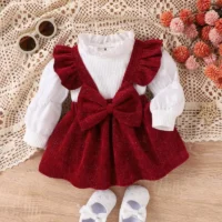 Baby girl red pinafore dress set with sparkly red pinafore, ruffled straps, large bow, and white ribbed top, displayed for catalog.
