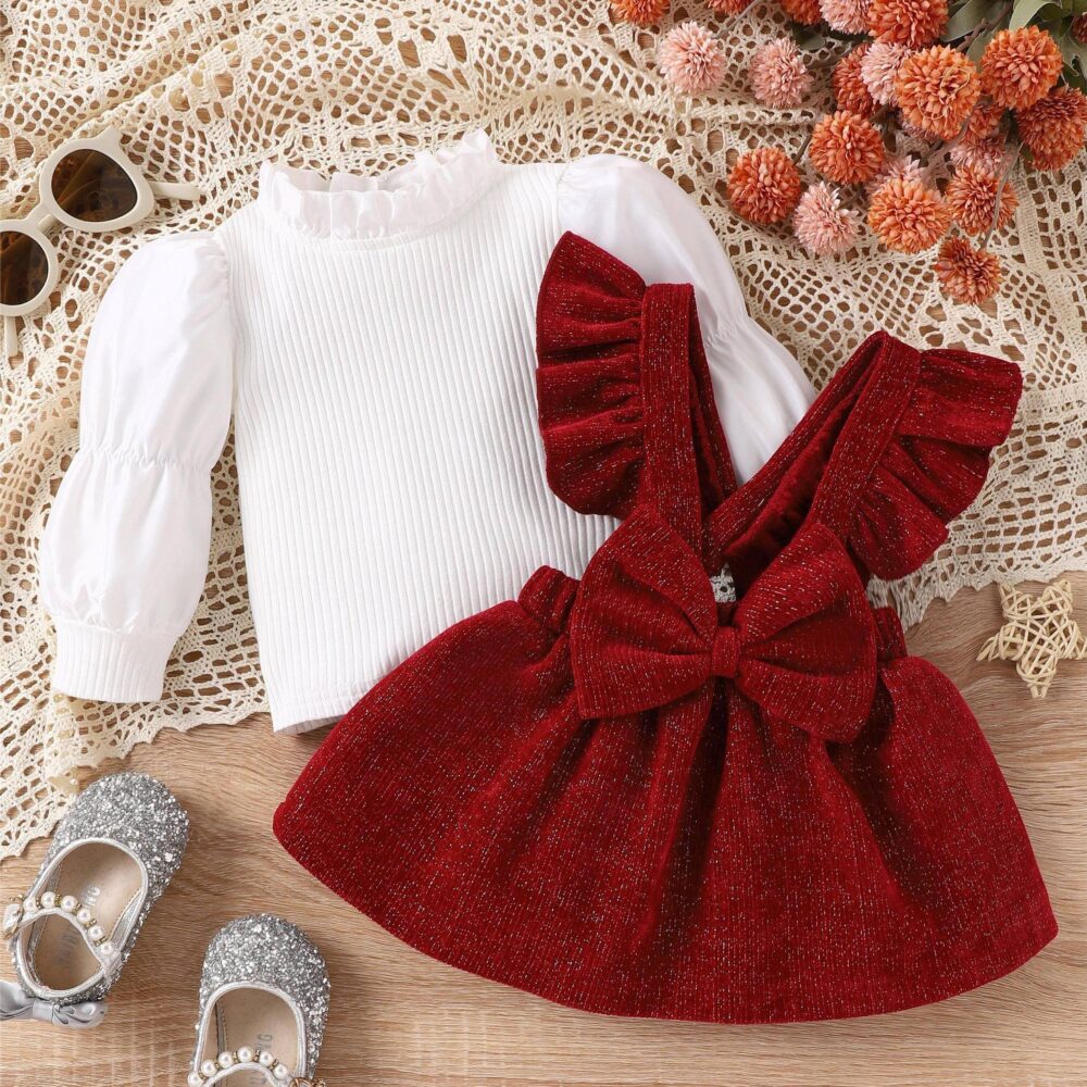 Baby girl red pinafore dress set with sparkly red pinafore, ruffled straps, large bow, and white ribbed top, displayed for catalog.