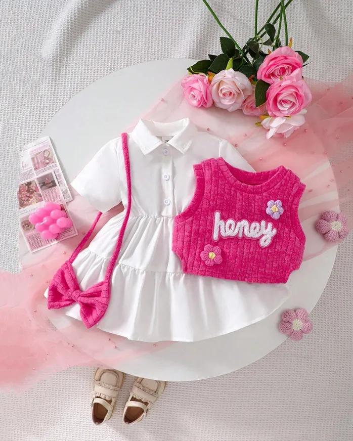 Girls white dress and pink knitted vest set with embroidery, floral appliqués, tiered skirt, and matching accessories, displayed for catalog