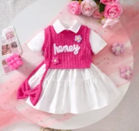 Girls white dress and pink knitted vest set with embroidery, floral appliqués, tiered skirt, and matching accessories, displayed for catalog