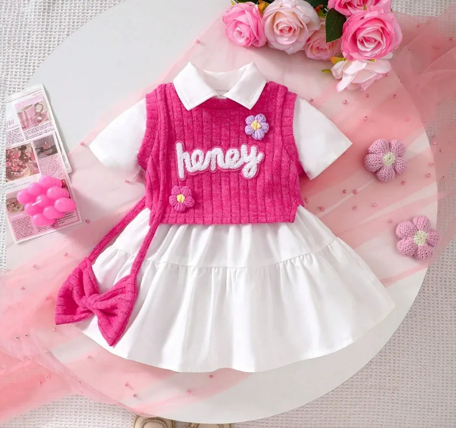 Girls white dress and pink knitted vest set with embroidery, floral appliqués, tiered skirt, and matching accessories, displayed for catalog