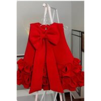 Red bow baby girl dress with sleeveless design, ruffle hem, and large decorative bow at the back, displayed for catalog