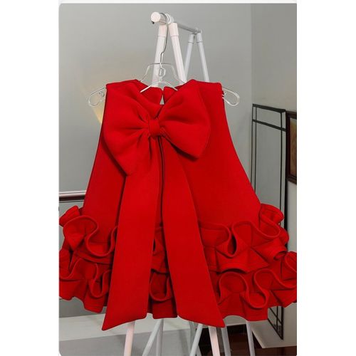 Red bow baby girl dress with sleeveless design, ruffle hem, and large decorative bow at the back, displayed for catalog