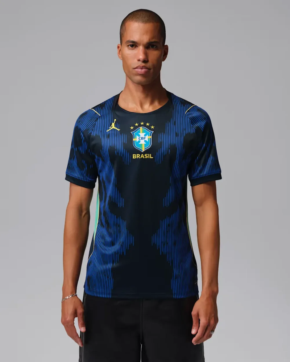 CBF+M+NK+DF+JSY+SS+STAD+AW3 A man modeling the official dark blue Brazil national football team away jersey featuring a bright blue abstract vertical pattern on tsapa with fast delivery in kigali, Rwanda