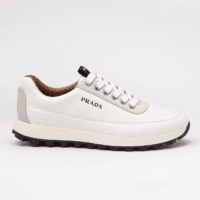 Lateral profile view of a luxury Prada low-top sneaker in white leather with a black treaded outsole — Premium Men's Designer Footwear Rwanda.