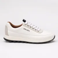 Lateral profile view of a luxury Prada low-top sneaker in white leather with a black treaded outsole — Premium Men's Designer Footwear Rwanda.