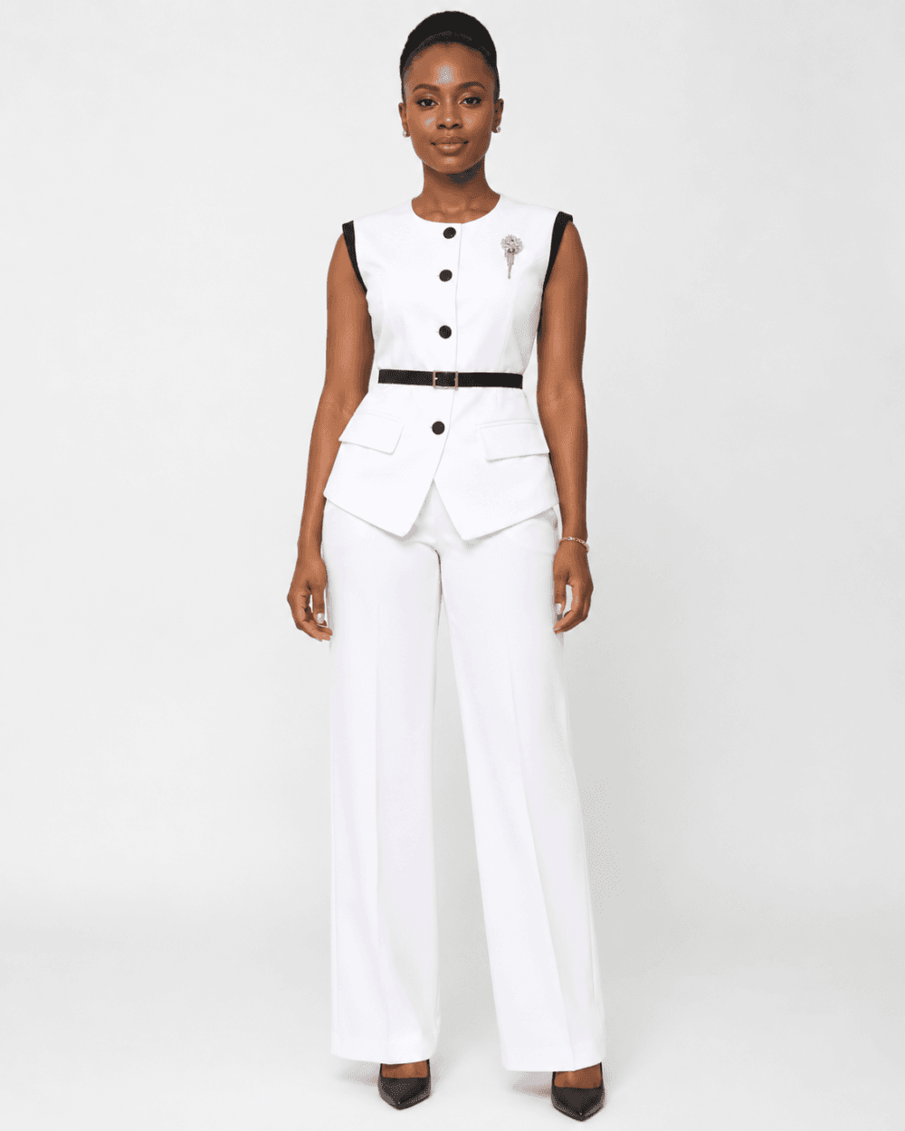 Women’s White Sleeveless Peplum Pantsuit Woman wearing a white sleeveless peplum pantsuit with black trim and wide-leg trousers