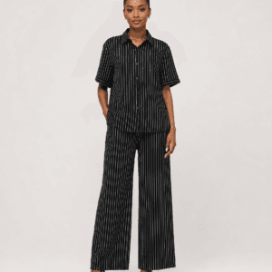 Full-length studio view of model wearing black pinstripe short-sleeve button-down shirt and wide-leg trousers set — Women's Fashion Rwanda.